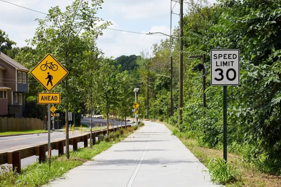 Paved Atlanta Beltline trail segment next to street with bike and pedestrian crossing sign and 30 mph speed limit sign.